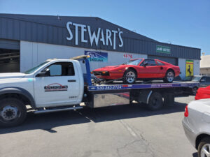 A white flatbed tow truck from Anthony's Towing & Transportation transporting a red sports car in Yuba City, CA.