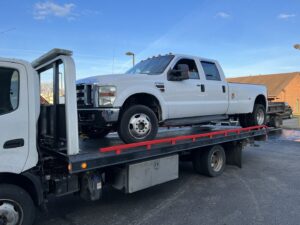 A white Ford F-350 dually pickup truck being transported on a flatbed tow truck by Anytime towing services in Columbus, OH.