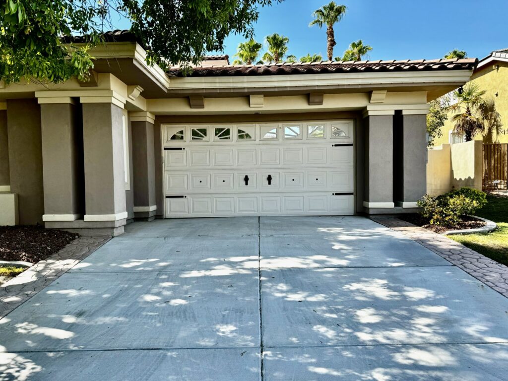 A white garage door with decorative hardware and windows installed on a residential home by Apex Garage Doors LLC in Las Vegas, NV