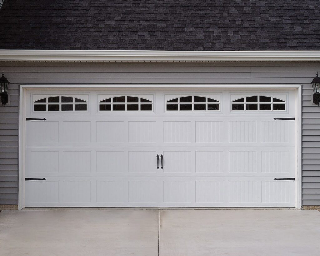 A classic white garage door with decorative windows and black hardware installed by The Door Man - Garage Doors & Openers in Reno, NV