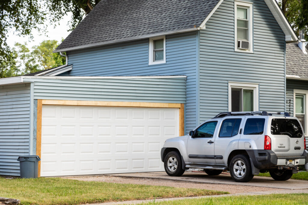 A newly installed white garage door on a blue residential house by Bob McDonald Garage Door LLC in Columbus, NE.