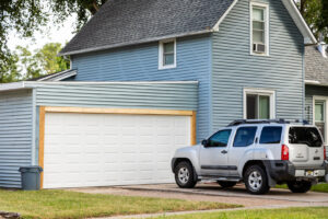 A newly installed white garage door on a blue residential house by Bob McDonald Garage Door LLC in Columbus, NE.