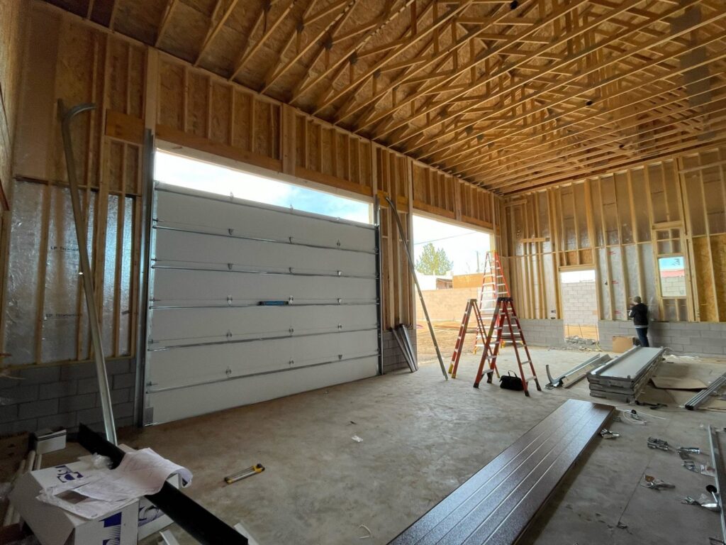 A white garage door being installed in a new construction garage by Excellence Garage Doors LLC in Albuquerque, NM.