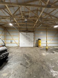 A newly installed white garage door with an opener inside a large building by Woodwards Overhead Door Co. in Topeka, KS