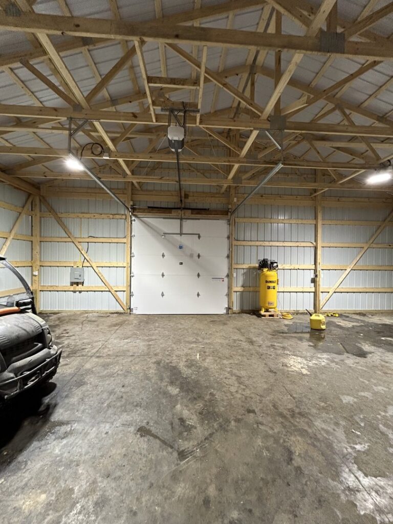 A newly installed white garage door with an opener inside a large building by Woodwards Overhead Door Co. in Topeka, KS