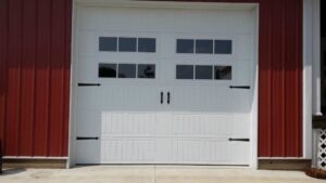 White garage door with windows and decorative hardware on a red building by Cedar Valley Garage Doors in Waterloo, IA