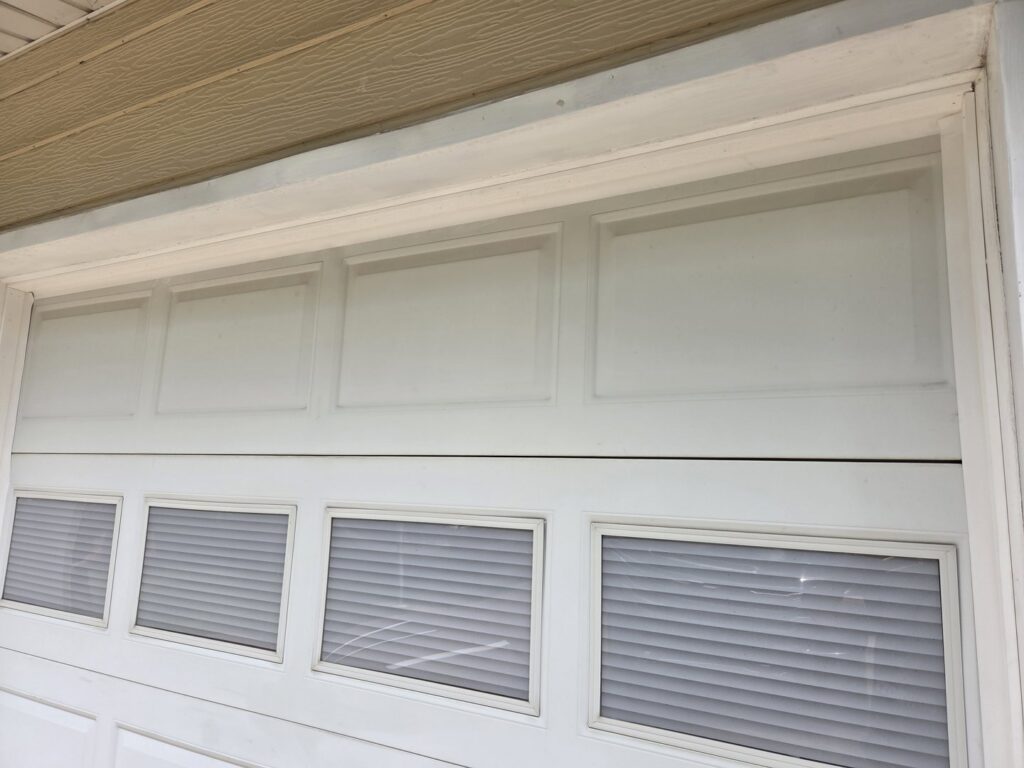 Close-up detail of a white garage door with windows and internal blinds installed by The Door Pros in Wichita, KS