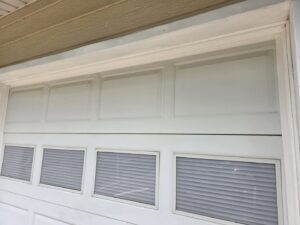 Close-up detail of a white garage door with windows and internal blinds installed by The Door Pros in Wichita, KS