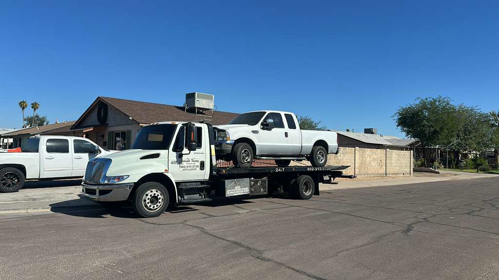 A white Honda Accord sedan being transported on a flatbed tow truck by Crisanto Towing in Phoenix, AZ.