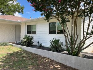 A home featuring a combination of white horizontal siding and stone accents, installed by Ideal Siding Austin in Austin, TX.