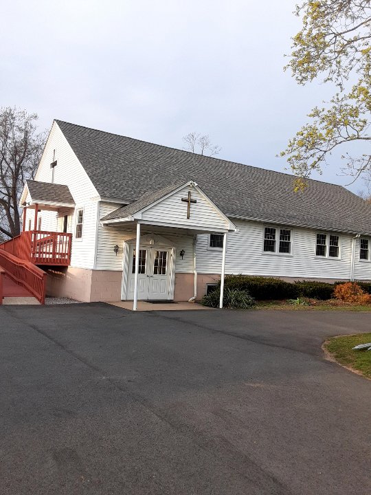 A church building featuring clean white horizontal siding and a gray shingle roof by DL Roofing and Siding in New Haven, CT