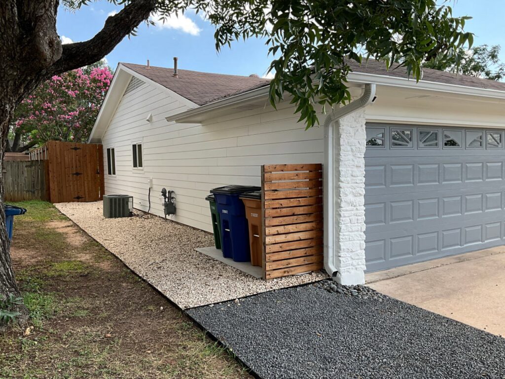 A house with white horizontal siding and a modern gray garage door, a completed project by Ideal Siding Austin in Austin, TX.