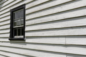 Detailed view of white horizontal siding with a black-framed window, a project by Ideal Siding Nashville, TN.