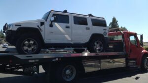 A white Hummer H2 SUV secured on a flatbed tow truck by 101 auto towing inc in San Jose, CA.