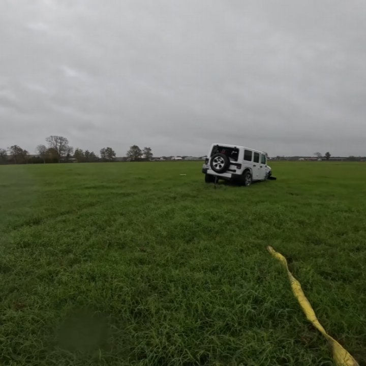 A white Jeep stuck in a grassy field, awaiting recovery by Columbus Towing in Columbus, GA.