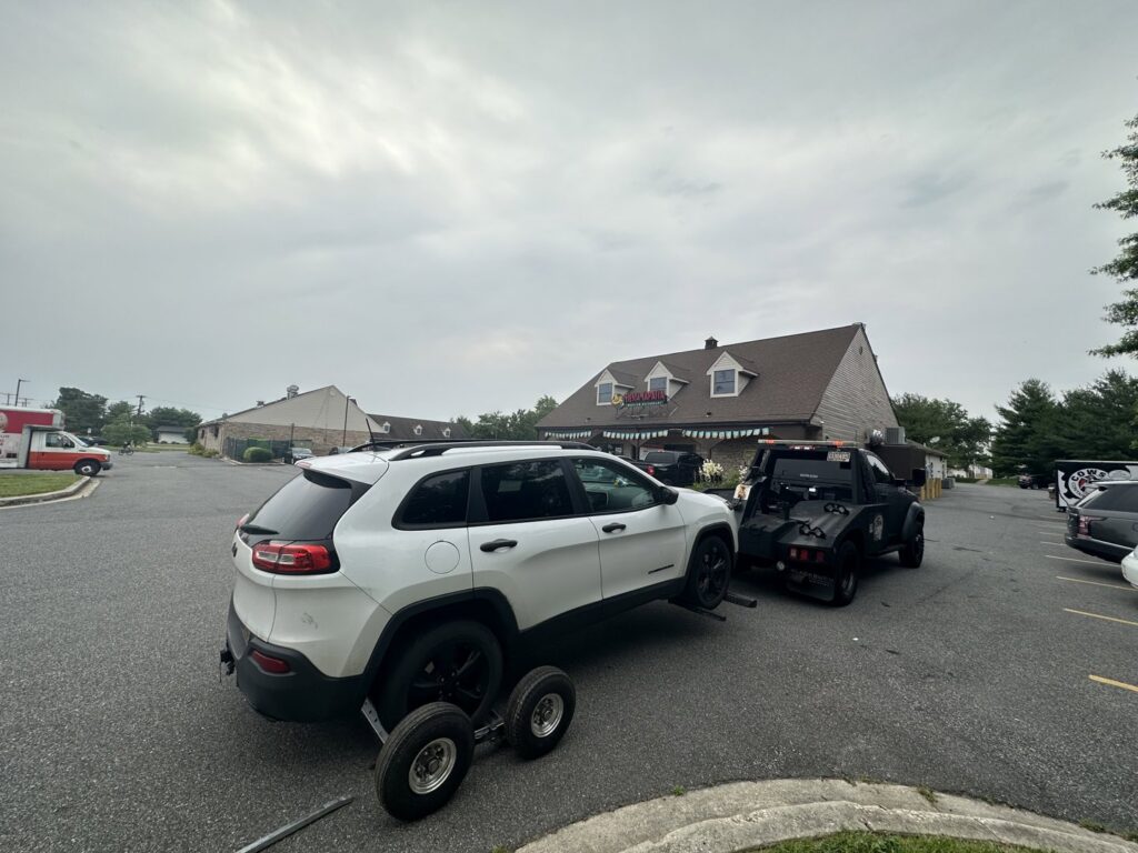 A white Jeep SUV being towed with dollies by Nacho Transports llc in Middletown, DE.