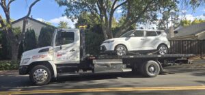 A white Kia Soul being towed on a flatbed tow truck by Ibanez Towing Service LLC in San Jose, CA.