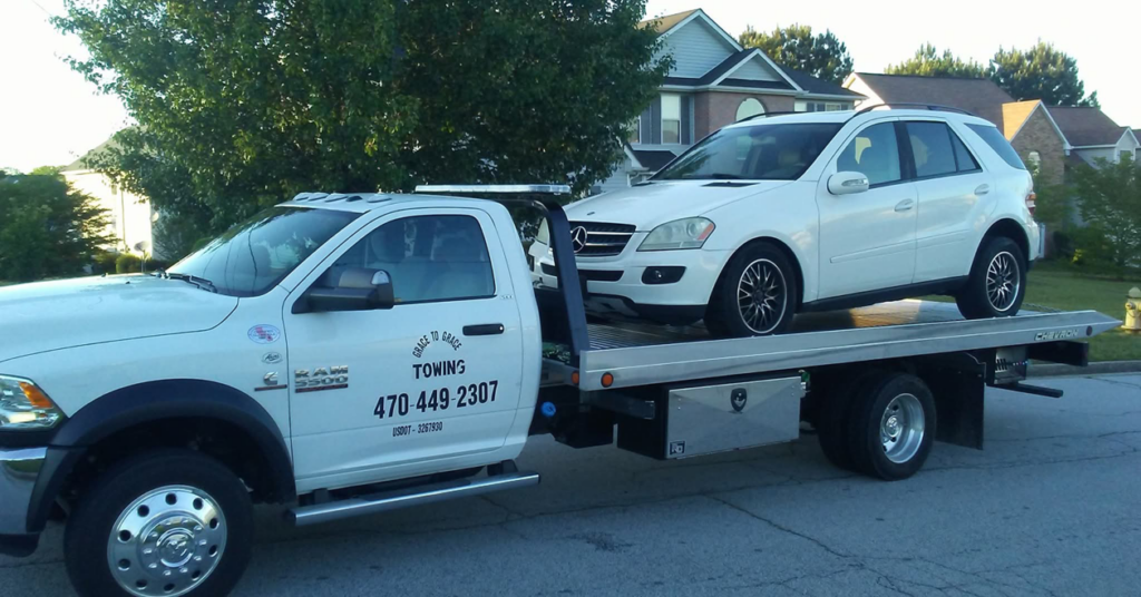 A white Mercedes SUV being transported on a flatbed tow truck by Grace to Grace Towing in Atlanta, GA.