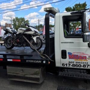 A white motorcycle secured on a flatbed tow truck by Milan Towing inc. in Milan, MI.