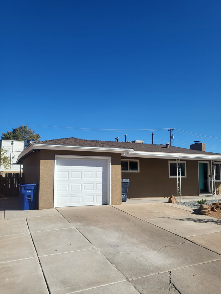 Exterior view of a house with a new white panel garage door installed by Spartan Garage Doors and More in Albuquerque, NM.