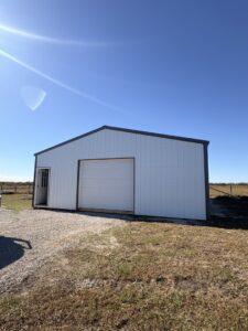 A newly installed white panel garage door on a white metal building by The Door Pros in Wichita, KS