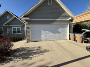 A white panel garage door on a residential house, showcasing a typical installation by Laramie Garage Doors in Laramie, WY.