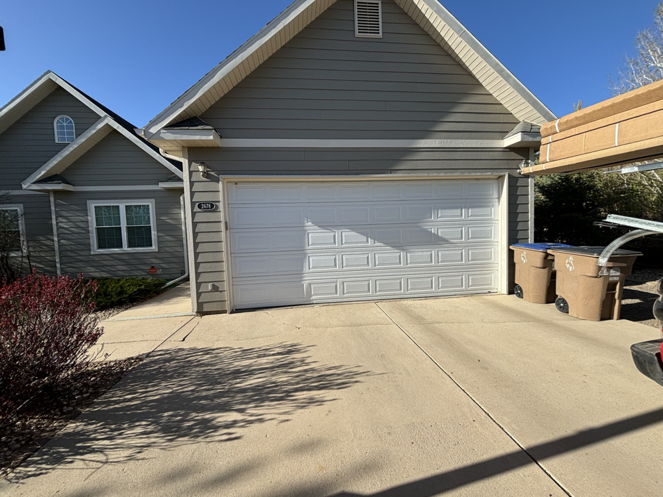 A white panel garage door on a residential house, showcasing a typical installation by Laramie Garage Doors in Laramie, WY.