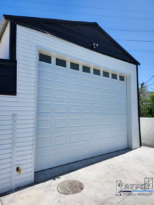 A newly installed white paneled garage door on a modern building by Layton Doors in West Jordan, UT.