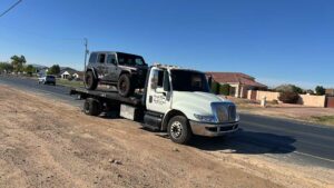 A white passenger van being transported on a flatbed tow truck by Crisanto Towing in Phoenix, AZ.