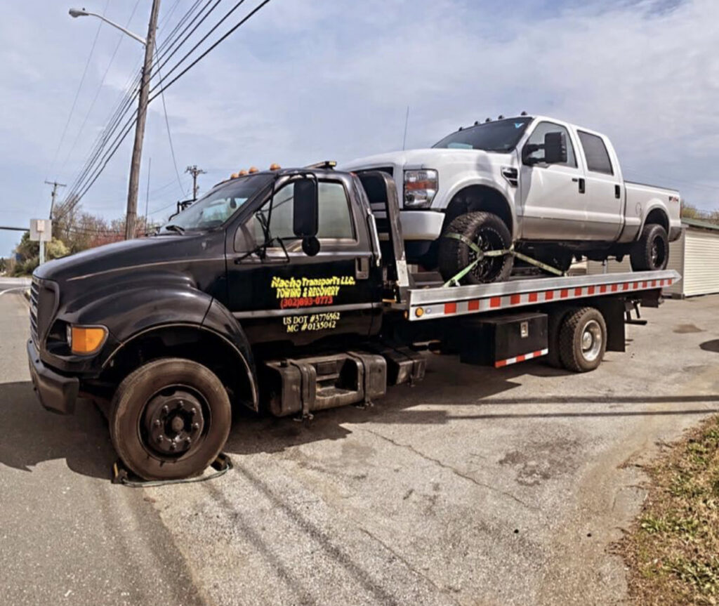 A white pickup truck loaded onto a flatbed tow truck from Nacho Transports llc in Middletown, DE.