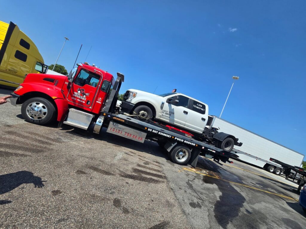 A white pickup truck being transported on a flatbed tow truck by Vatos Locos Towing in Cincinnati, OH.