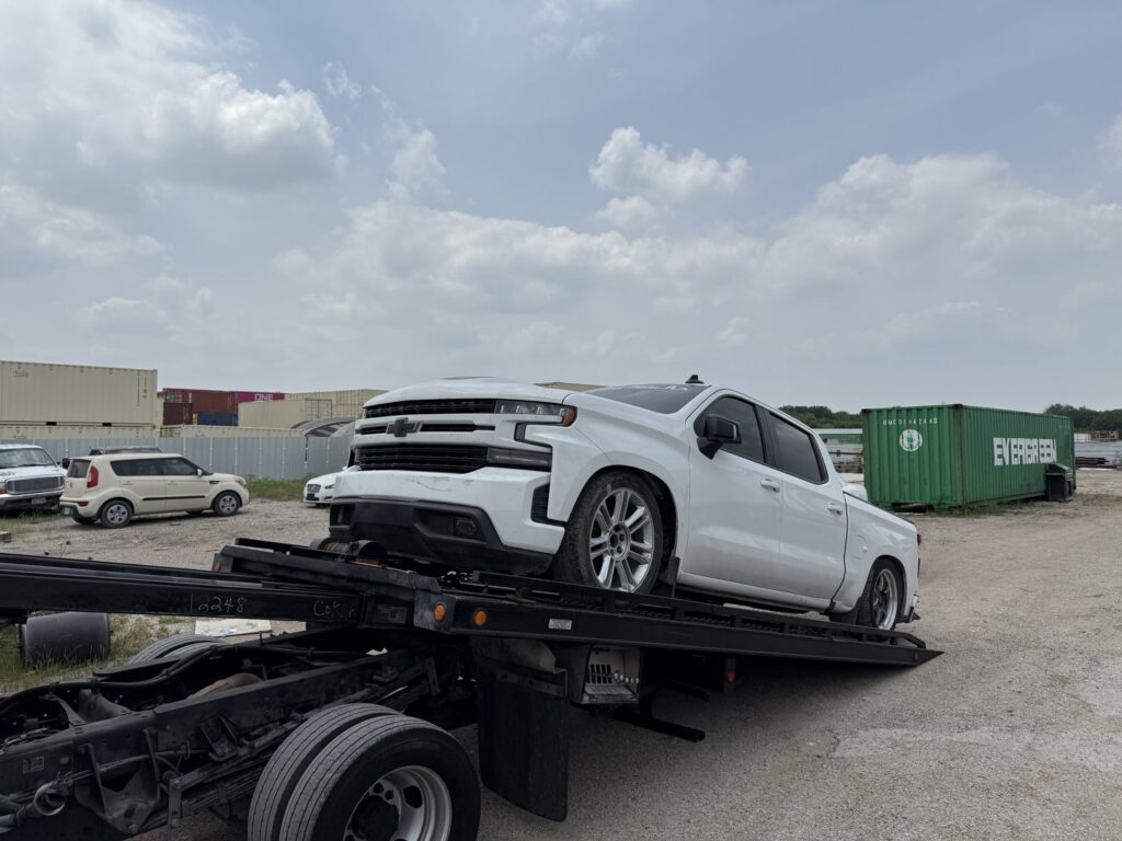 A white pickup truck being loaded onto a flatbed tow truck for RDZ Towing Service 24/7 in Dallas, TX.