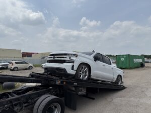 A white pickup truck being loaded onto a flatbed tow truck for RDZ Towing Service 24/7 in Dallas, TX.