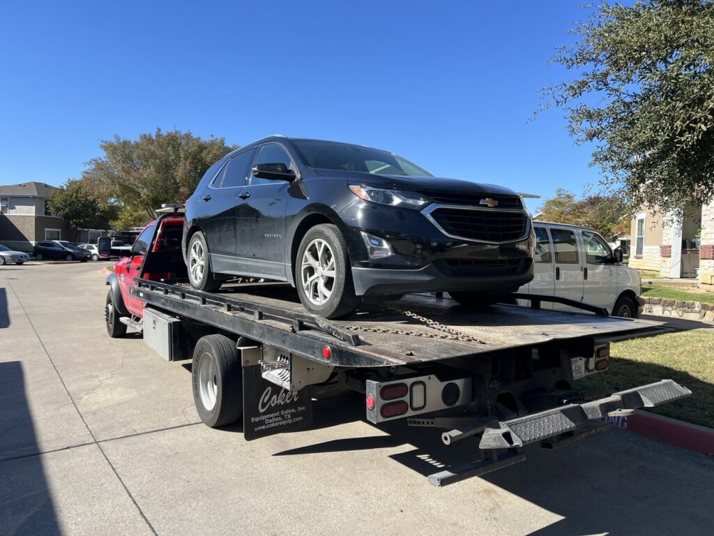 A white pickup truck fully loaded on a flatbed tow truck for RDZ Towing Service 24/7 in Dallas, TX.