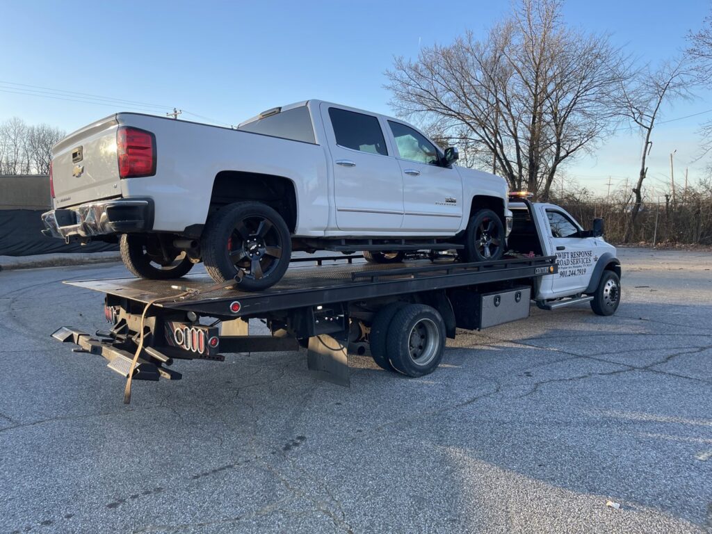A white pickup truck loaded onto a flatbed tow truck, providing towing services by Swift Response Road Services, LLC in Memphis, TN.