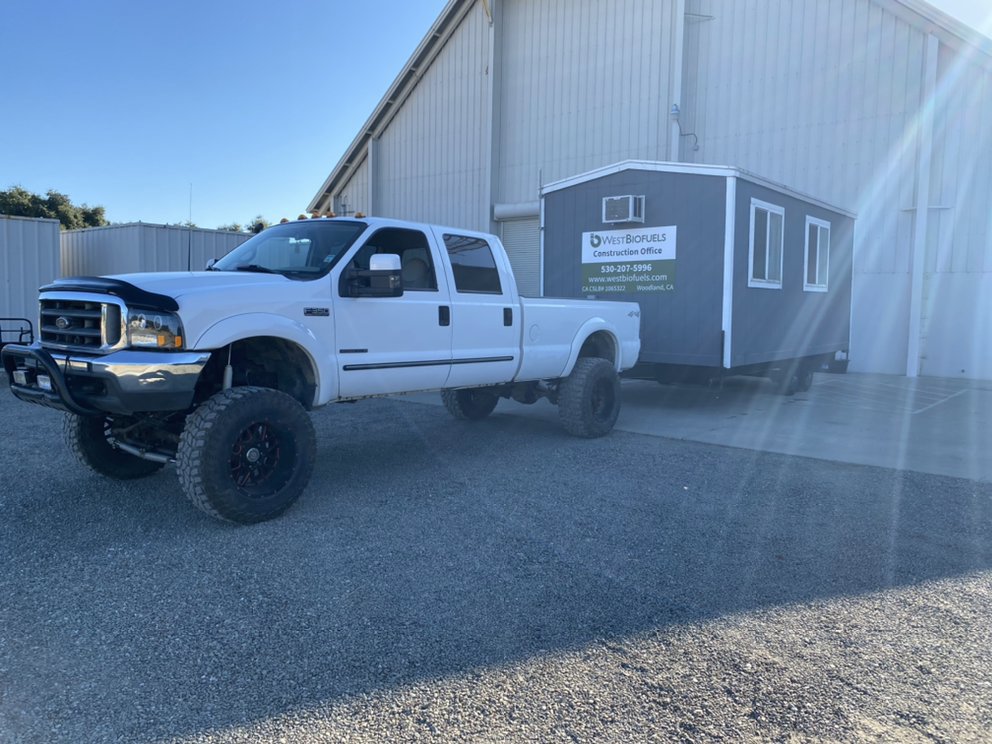 A white pickup truck from Anthony's Towing & Transportation towing a portable construction office in Yuba City, CA.