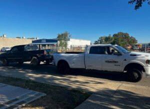 A white Anthony's Towing & Transportation pickup truck actively towing a dark pickup truck in Yuba City, CA.