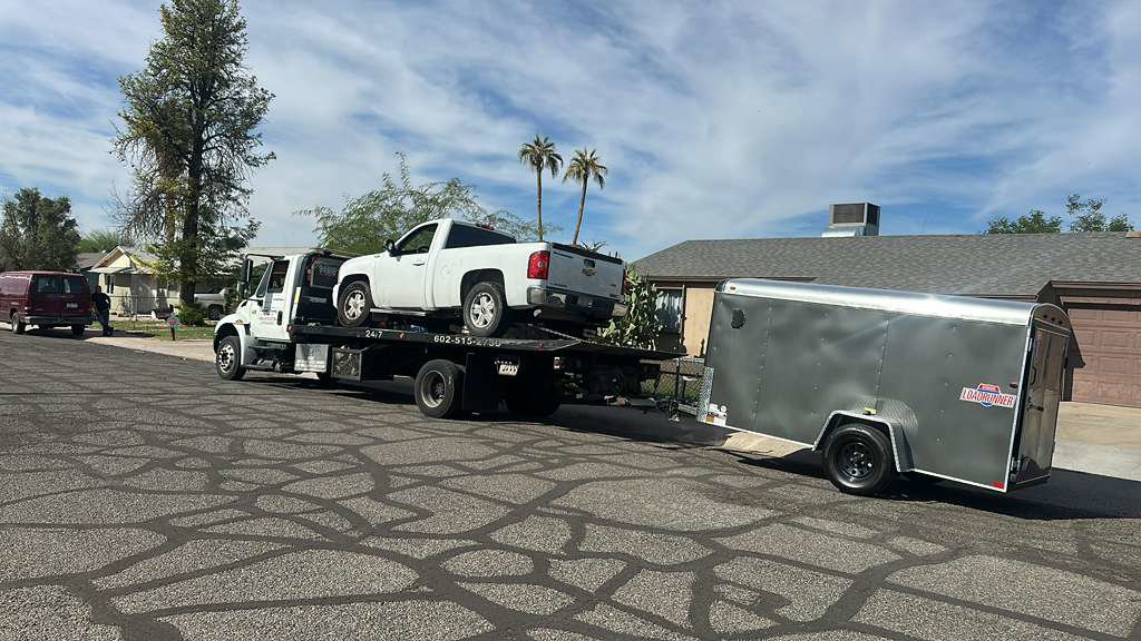 A white pickup truck and an enclosed trailer being transported by Crisanto Towing in Phoenix, AZ.