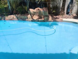 A white pool vacuum hose visible in a swimming pool by Suburban Pool Company in Germantown, WI.