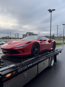 A white Porsche sports car being transported on a flatbed tow truck by Harpeth Towing & Recovery in Franklin, TN.