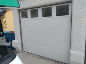 An exterior view of a white sectional garage door with square windows installed by Cactus Garage Doors, Inc. in North Las Vegas, NV.