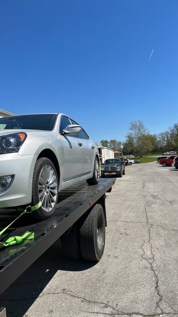 A white sedan loaded onto a flatbed tow truck for transport by Tow Truck Company in Johnson City, TN.