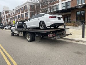 A white sedan loaded onto a flatbed tow truck, providing towing services by Swift Response Road Services, LLC in Memphis, TN.