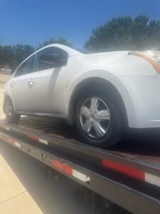 A white sedan partially loaded onto a flatbed tow truck by Black Rhino Towing in Denver, CO.