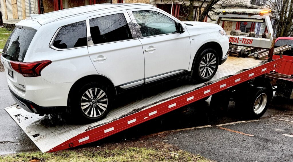 A white SUV being loaded onto a flatbed tow truck by RonniesTowing&Recovery in Bryan, TX