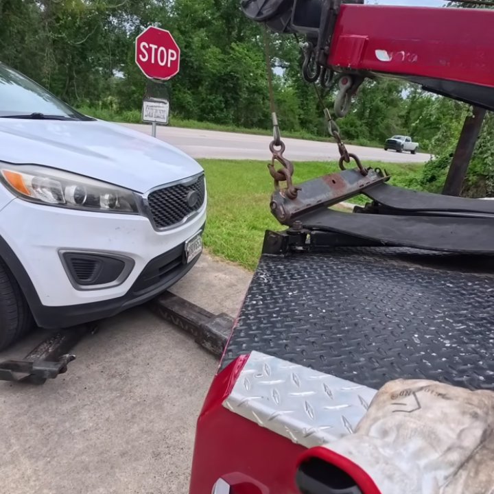 A white SUV being loaded onto a flatbed tow truck for a towing service by Fort Benning Towing in Columbus, GA