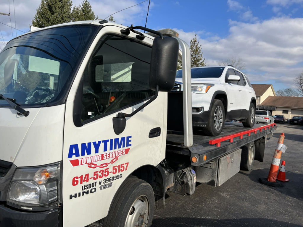 A white SUV being transported on a flatbed tow truck by Anytime towing services in Columbus, OH.
