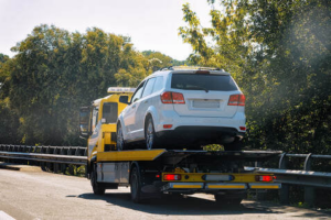 A white SUV being transported on a yellow flatbed tow truck by DunRite Towing Jonesboro in Jonesboro, AR.