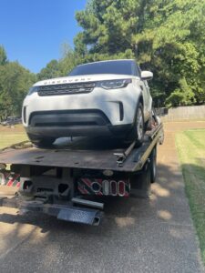 A white SUV loaded onto a flatbed tow truck, providing towing services by Swift Response Road Services, LLC in Memphis, TN.