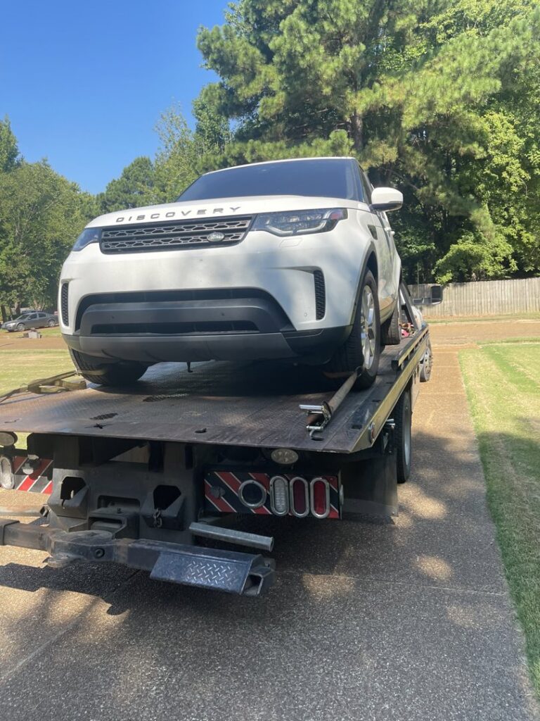 A white SUV loaded onto a flatbed tow truck, providing towing services by Swift Response Road Services, LLC in Memphis, TN.